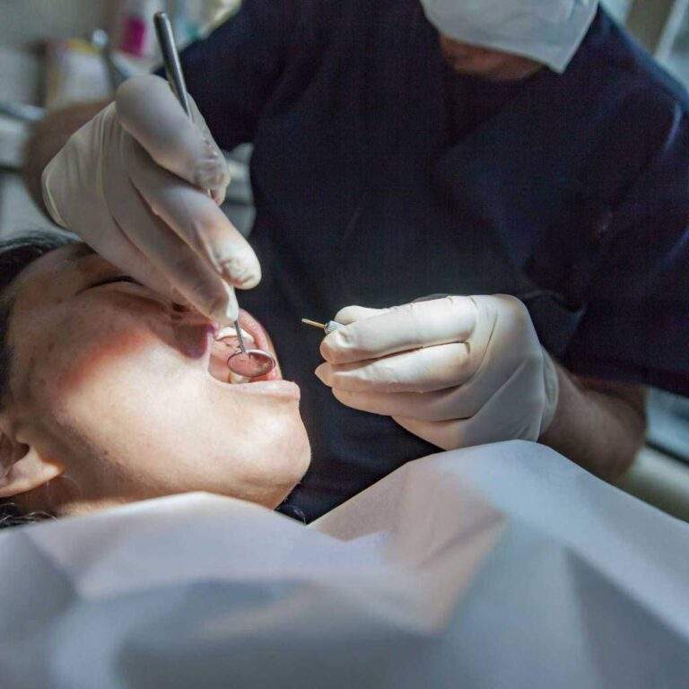 Dentista con guantes atendiendo a un paciente en el sillón