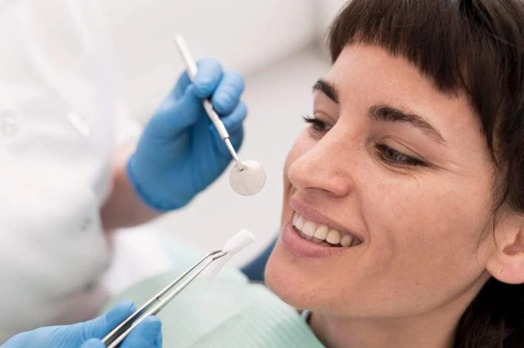 Paciente mirándose la sonrisa en un espejo junto a la dentista